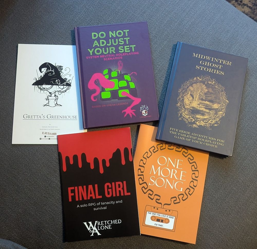 Photo of 4 TTRPG books from Ex Stasis Games laid out next to each other: Do Not Adjust Your Set (A collection of system-neutral TTRPG scenarios based on urban legends), Midwinter Ghost Stories (A collection of five system-neutral roleplaying scenarios to terrify and delight), Final Girl (A solo RPG of tenacity and survival), One More Song (A journalling role-playing game based on the myth of Orpheus). 
In addition to the books is a small one-shot pamphlet called Gretta's Greenhouse by Caesar Ink.