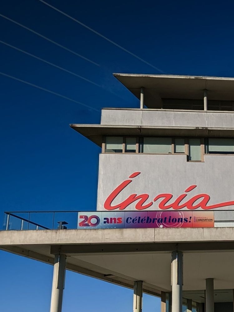 Bâtiment Inria avec ciel bleu et bannière Célébrations !