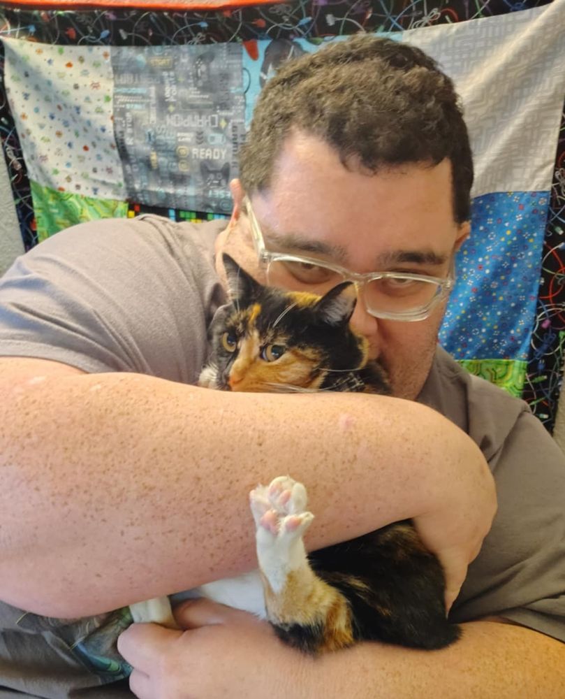 A picture of myself holding my cat. She is very unsure of me holding her, and her leg is sticking out, with her toes stretched out.