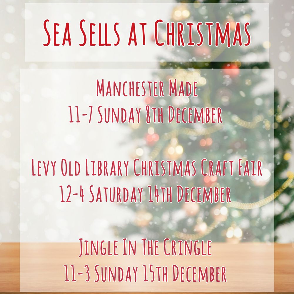 Red text with a white border on a semi-transparent white border reads:
Sea Sells At Christmas 
Manchester Made
11-7 Sunday 8th December 

Levy Old Library Christmas Craft Fair
12-4 Saturday 14th December 

Jingle In The Cringle 
11-3 Sunday 15th December 

Behind the text is a light wooden table surface in the foreground, a blurry decorated Christmas tree in the background in front of a grey wall
