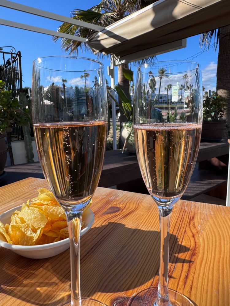 two glasses of rose cava sitting on a table in the sunshine 