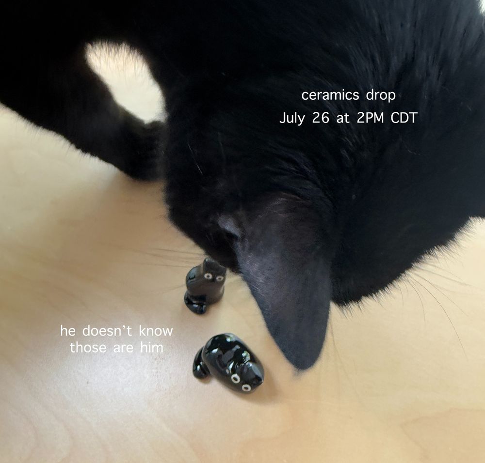 A black cat interrupting my photoshoot of black cat figurines. The text says "ceramics drop July 26 at 2PM CDT" and "he doesn't know those are him"