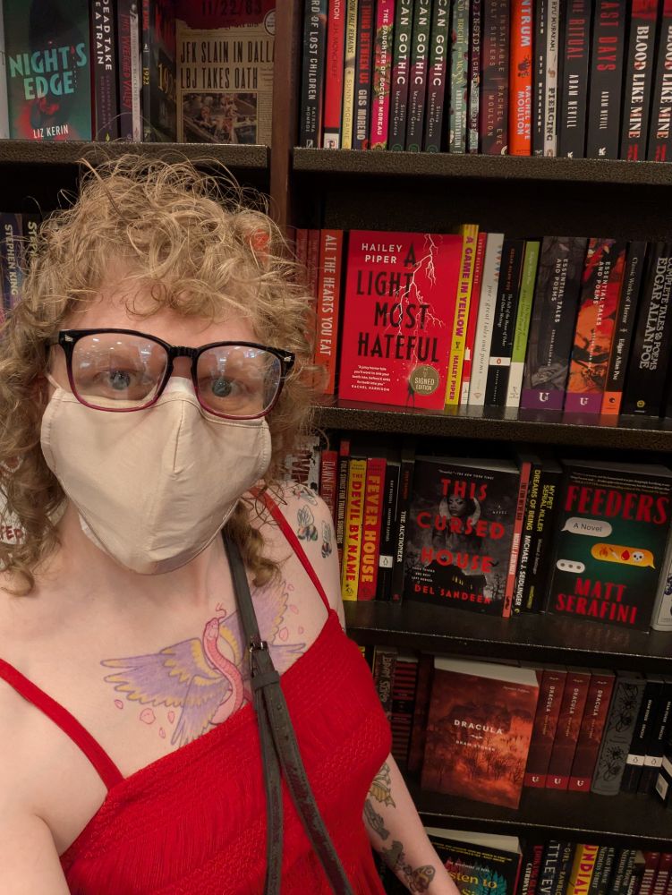 Hailey Piper in front of a Barnes and Noble shelf holding signed copies of some of her books