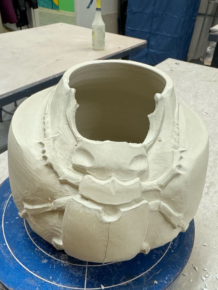 An in-progress porcelain pot with a carved European stag beetle. The carving is still rough and relatively unrefined.