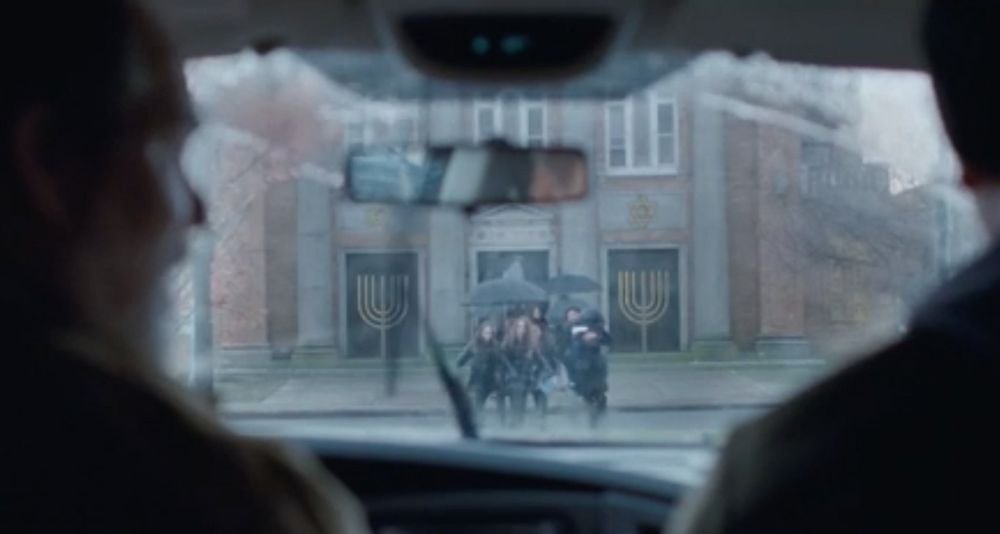 A man and his son sit in a truck watching people emerge from a synagogue in a scene from an ad in the Stand Up to Jewish Hate campaign