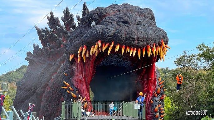 People zipline into the mouth of Godzilla at a theme park 