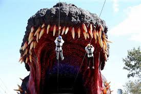 People zipline into the mouth of Godzilla at a theme park