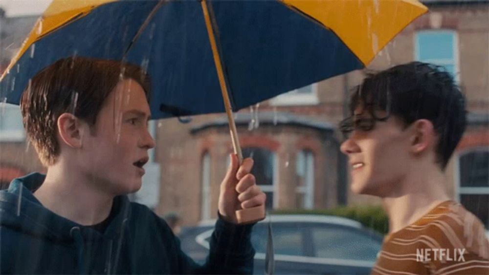 a man holding a blue and yellow umbrella with netflix written on the bottom