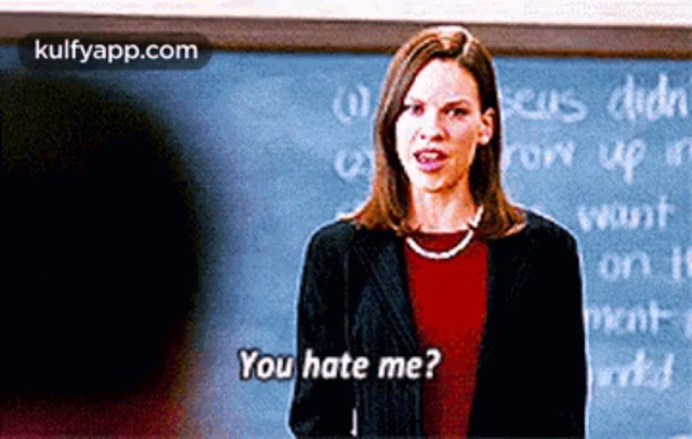 a woman is standing in front of a blackboard and saying you hate me ?