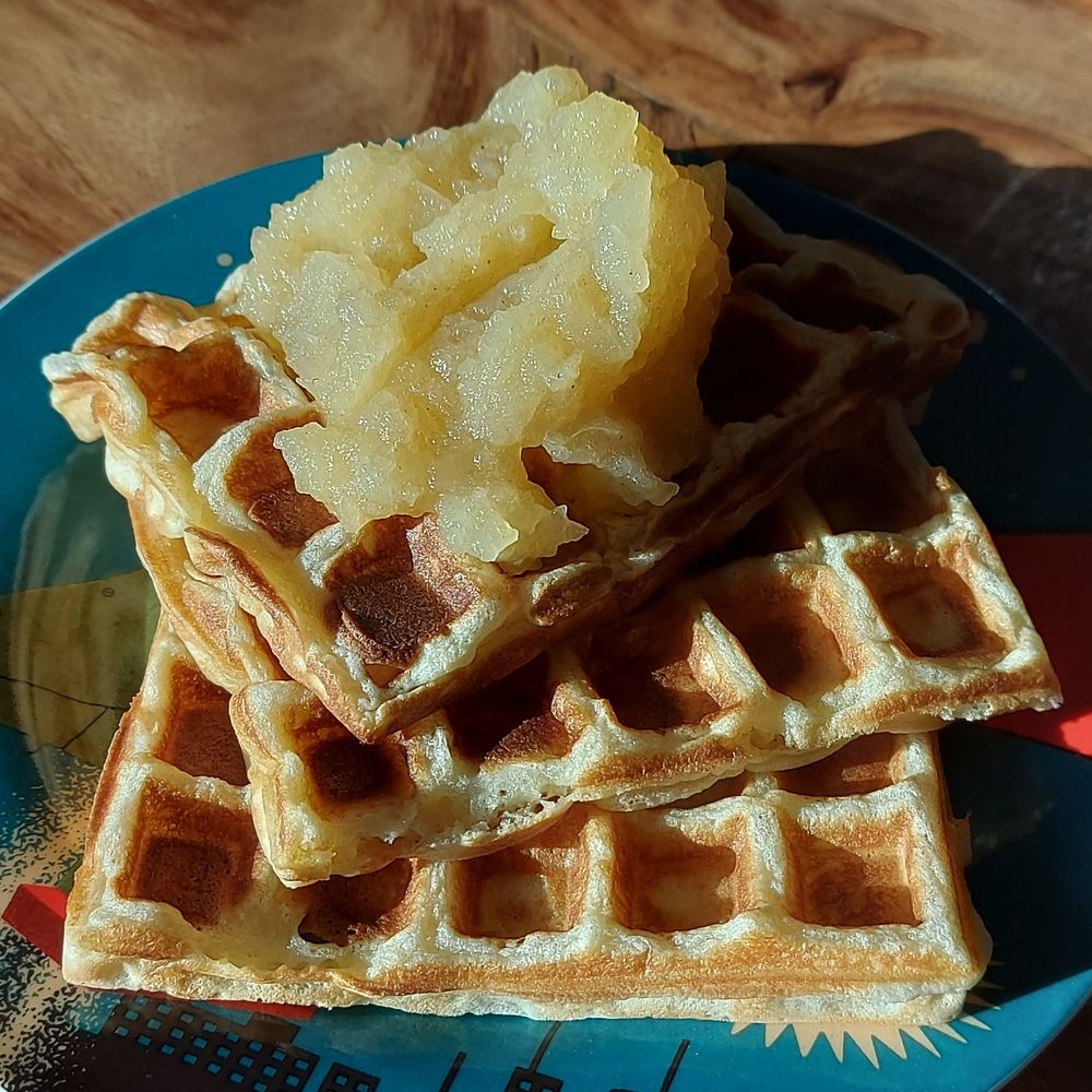 A closeup of a stack of homemade Belgian waffles with a topping of applesauce, laying on a blue plate. 

#treat #homemade #soulfood 