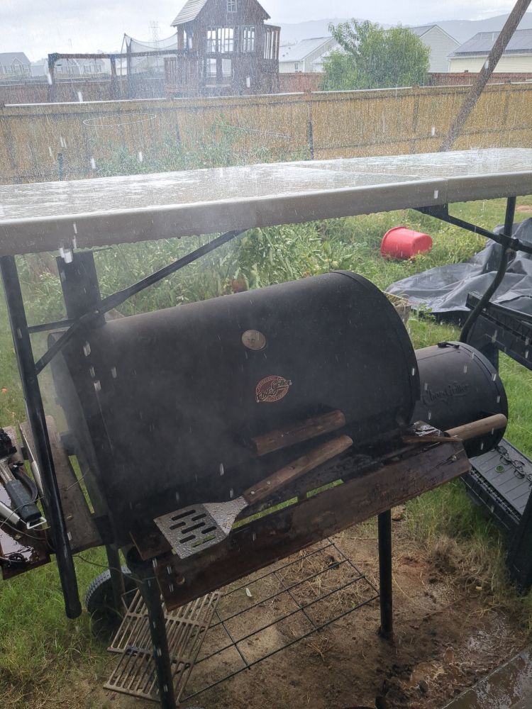 Portable table propped over a grill to keep the rain off