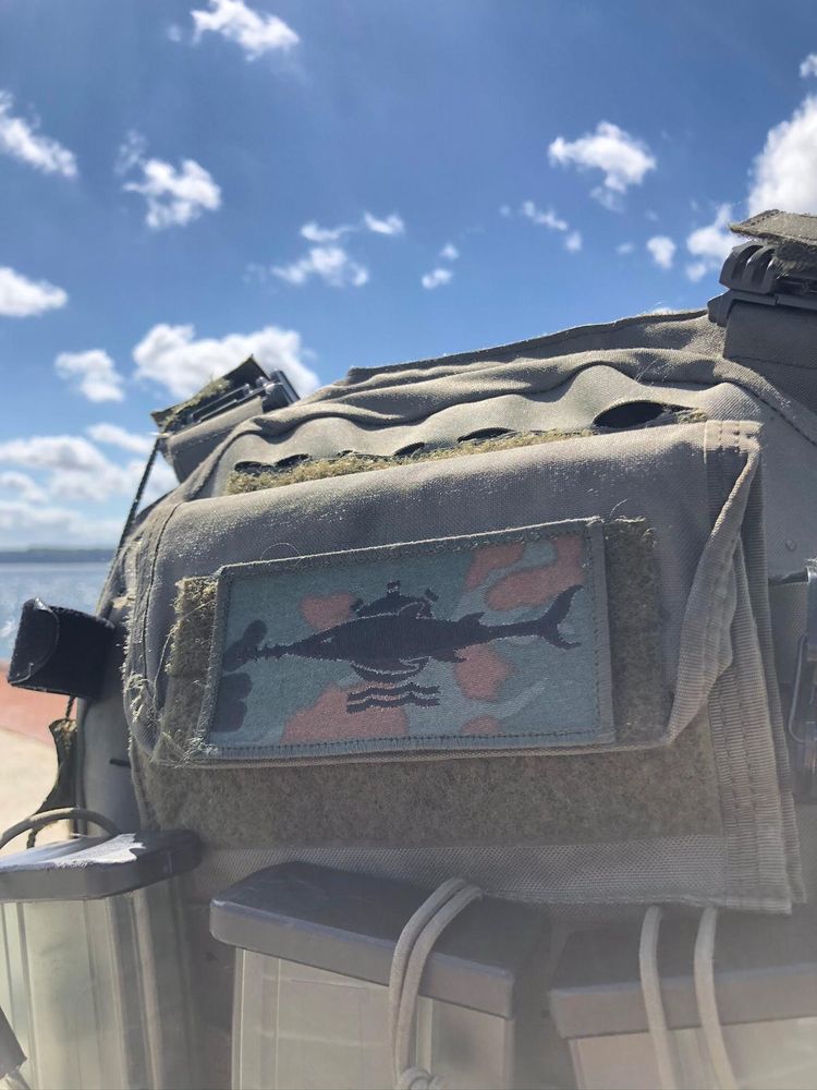 Ein Rucksack vor blauem Himmel mit dem Abzeichen der Minentaucher 