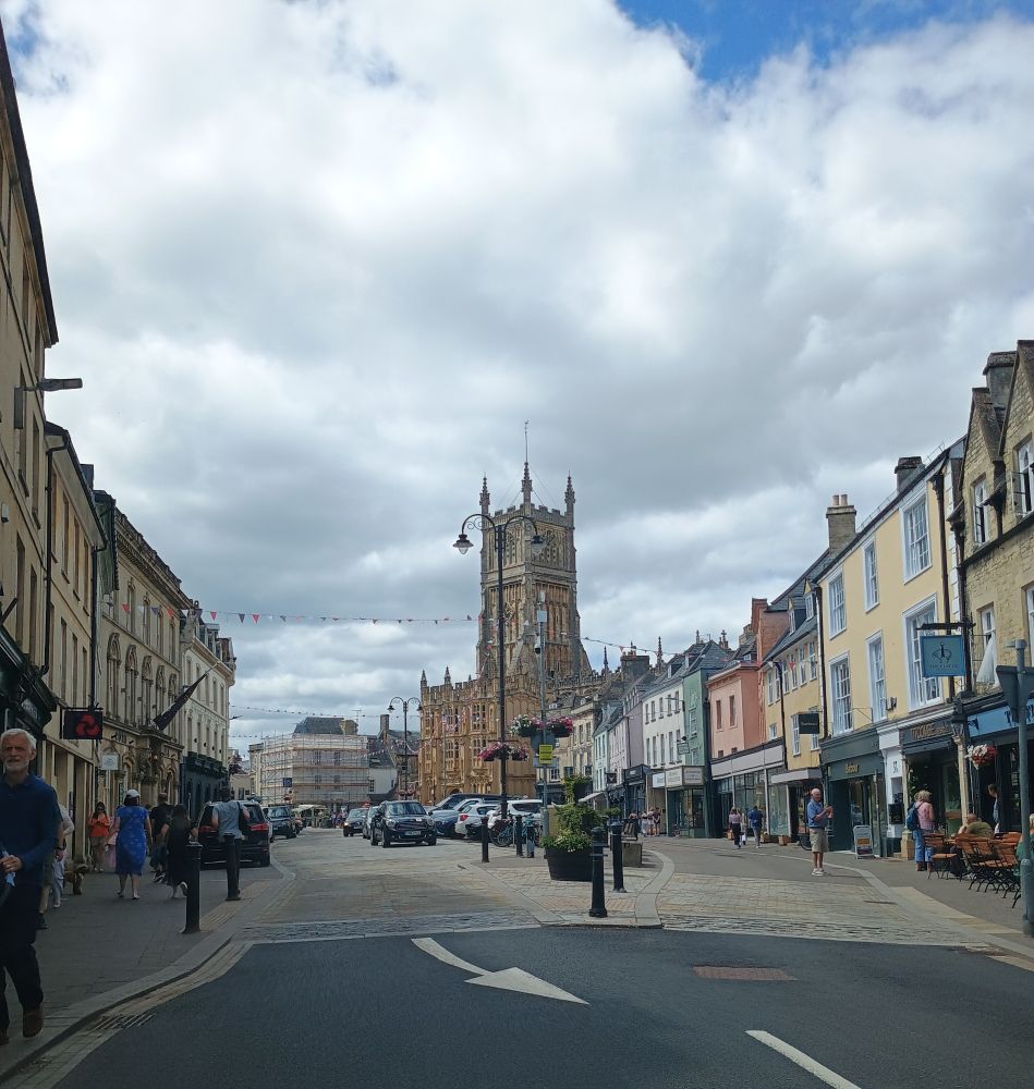 Photo of Cirencester town centre showing shops and St John the Baptist Church.