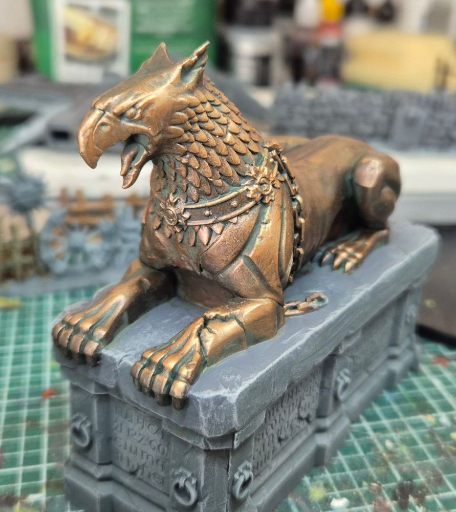A Stormcast statue of a Gryph-hound painted like aged bronze, on a stone plinth, three-quarter view from front right
