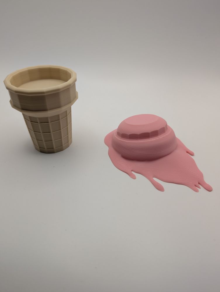 3D printed separate Tan colored ice cream cone and pink melting blob of ice cream on white background.