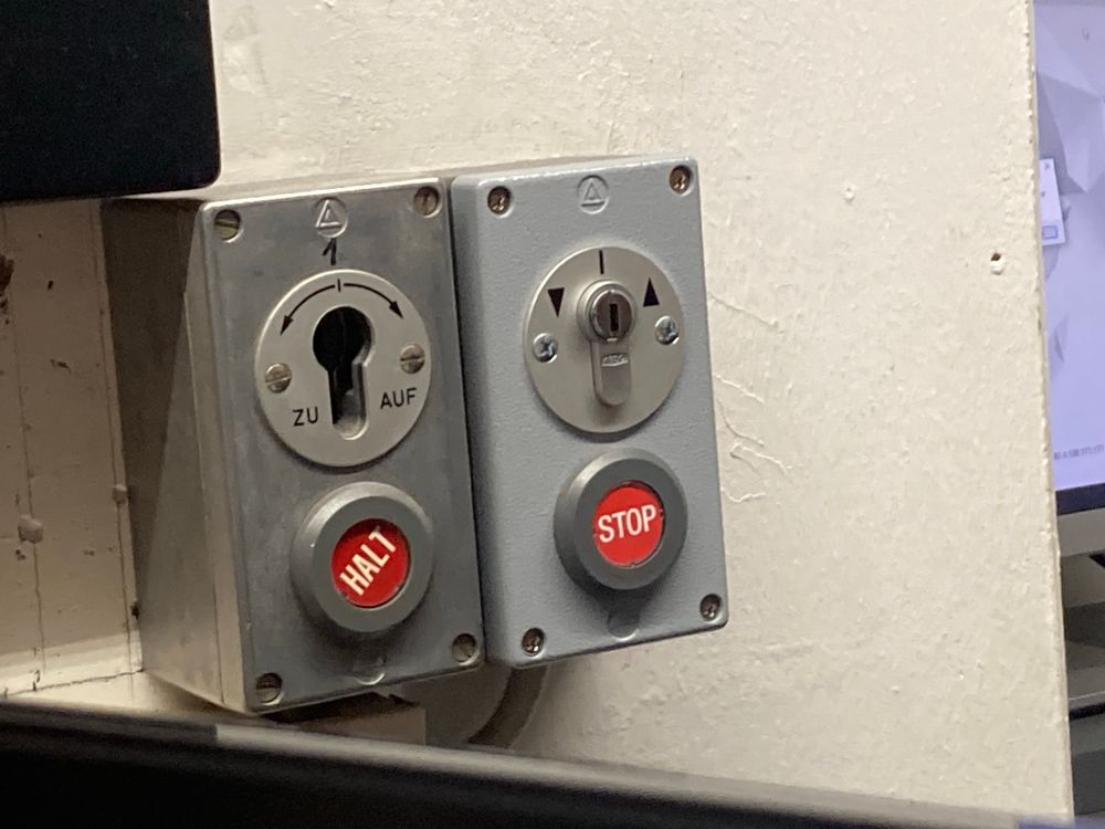 Zwei Not-Aus-Knöpfe, einer mit „Halt“, einer mit „Stop“ beschriftet.
