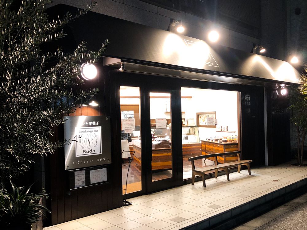 夜にライトアップされたブーランジェリースドウの店舗外観。温かい雰囲気と洗練されたデザインが特徴的なパン屋の佇まい。
