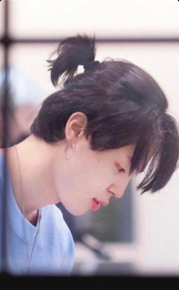 Jimin with a ponytail and wearing a blue tshirt.