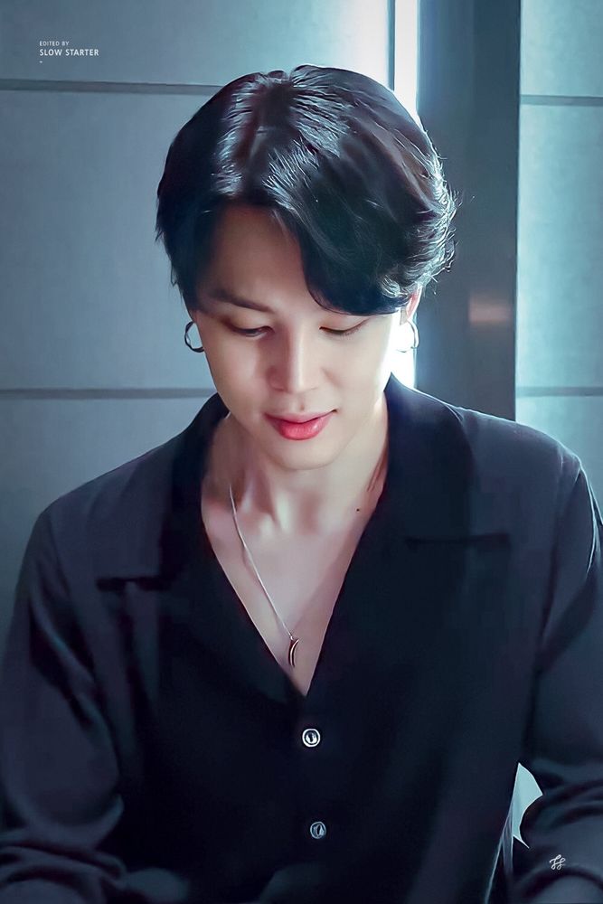 Jimin wearing a black.buttoned shirt.