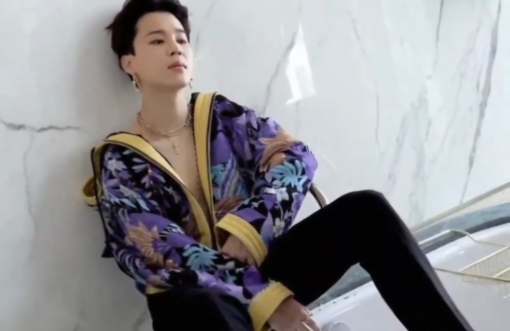 Jimin with an open blue textured jacket and black trousers.