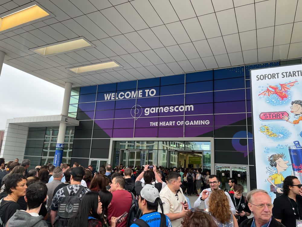 Puerta de la gamescon, con un letrero de bienvenida y mucha gente esperando