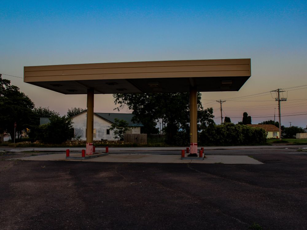 A photo of the covered area outside an abandoned gas station with the pumps removed 