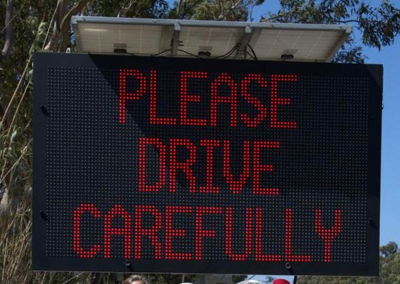 Road-side LED display reading PLEASE DRIVE CAREFULLY
