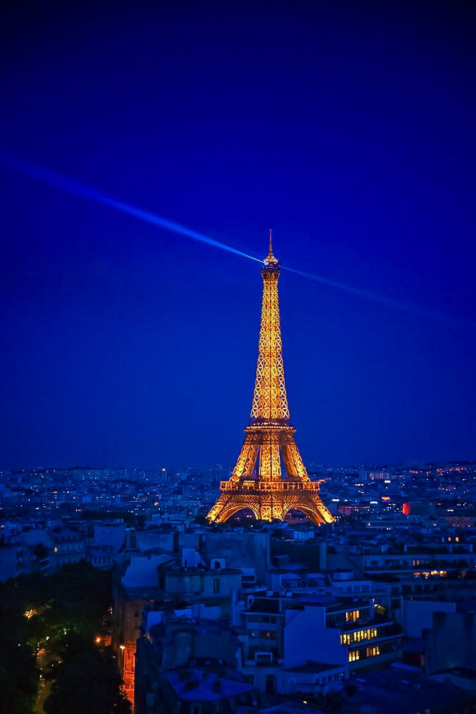 The Eiffel Tower seen at night, giving off a beam of light at the top 