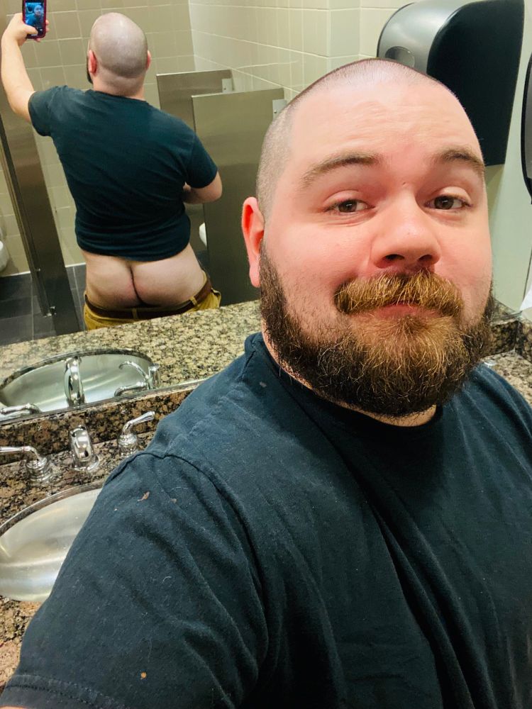 A public restroom selfie; I’m facing away from the mirror and smiling at the camera. In the reflection, my pants are down and butt cheeks are exposed.