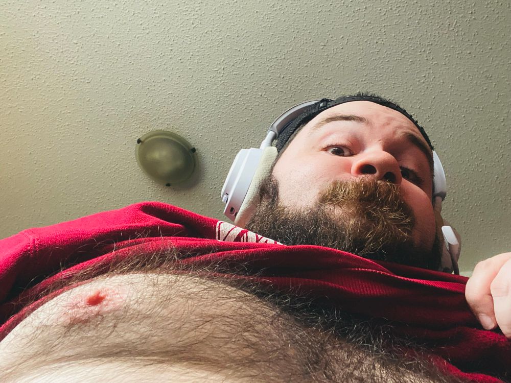 Me revealing my hair chest, looking down at the camera. 