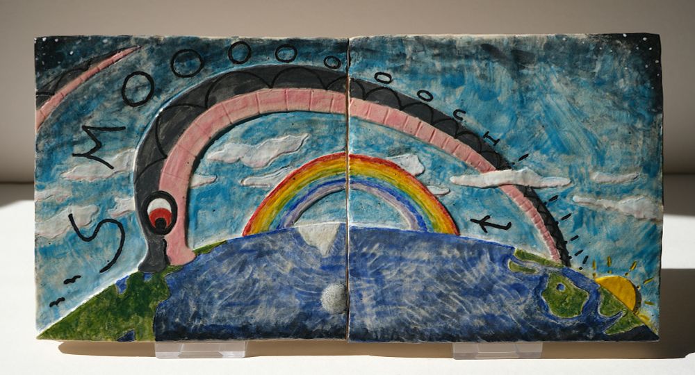 Cone 5ish ceramic glazed tile diptych of me, Asher the snake, as the world serpent Jörmungandr, reaching around the globe, over the rainbow, the clouds, and the oceans to give my boyfriend a tender kissy on the head. The word "SMOOOOOOCH!!!!!!" runs down my back, and the exclamation marks become the rays of the sun.

The bottom right of the left tile has a glassy blob glaze defect from where the kiln itself melted onto the tile. Really annoying!!!