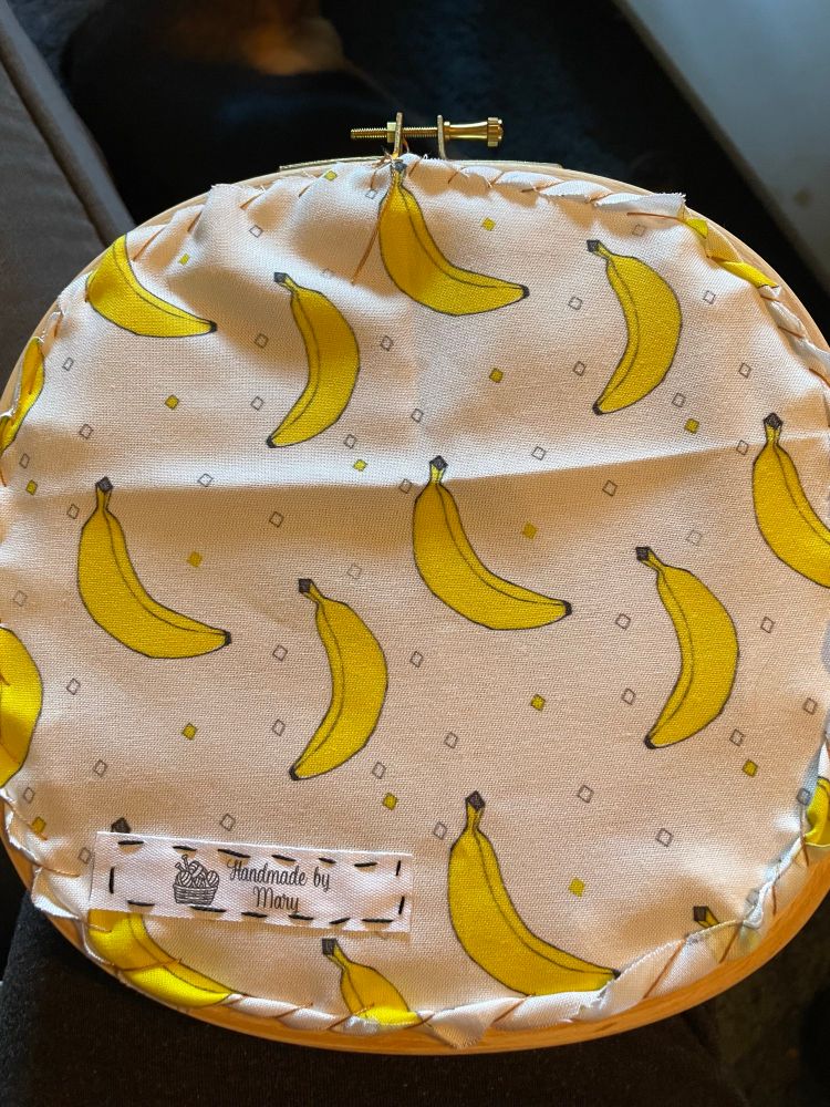 Hoop butt showing a sewn on tag that reads “handmade by Mary”. The fabric has bananas on it. 
