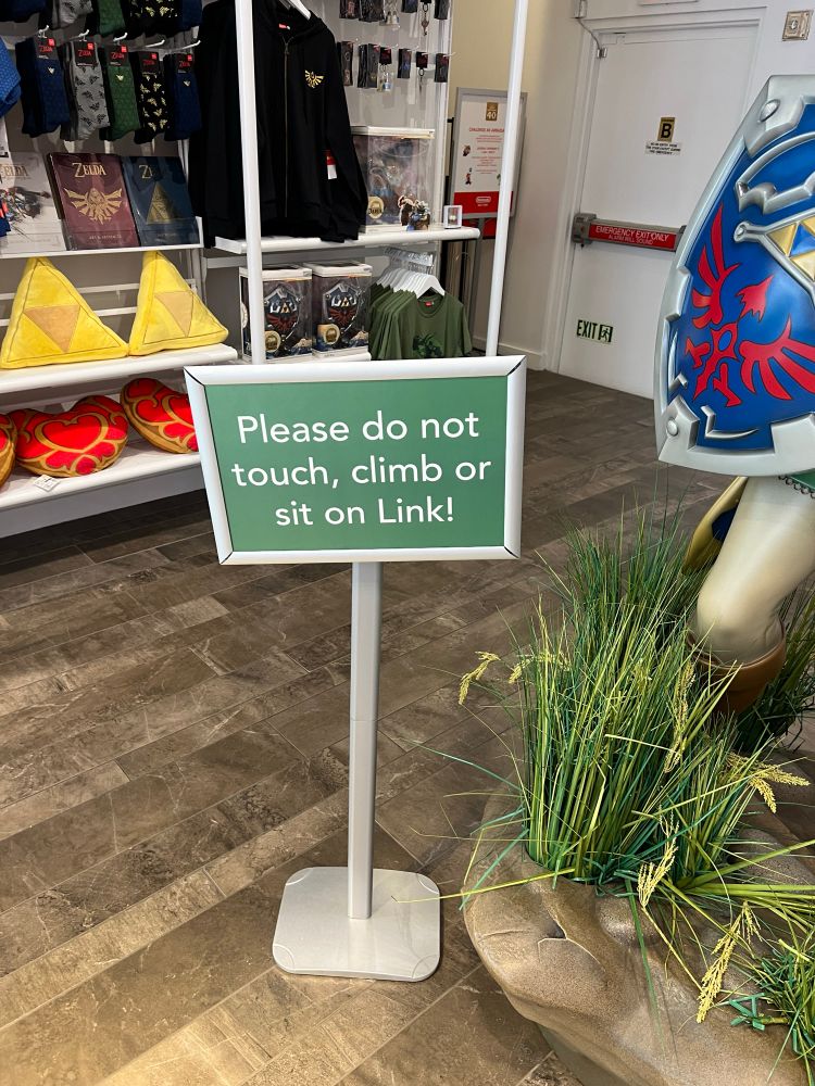 A sign in the New York Nintendo Store that reads “Please do not touch, climb, or sit on Link”