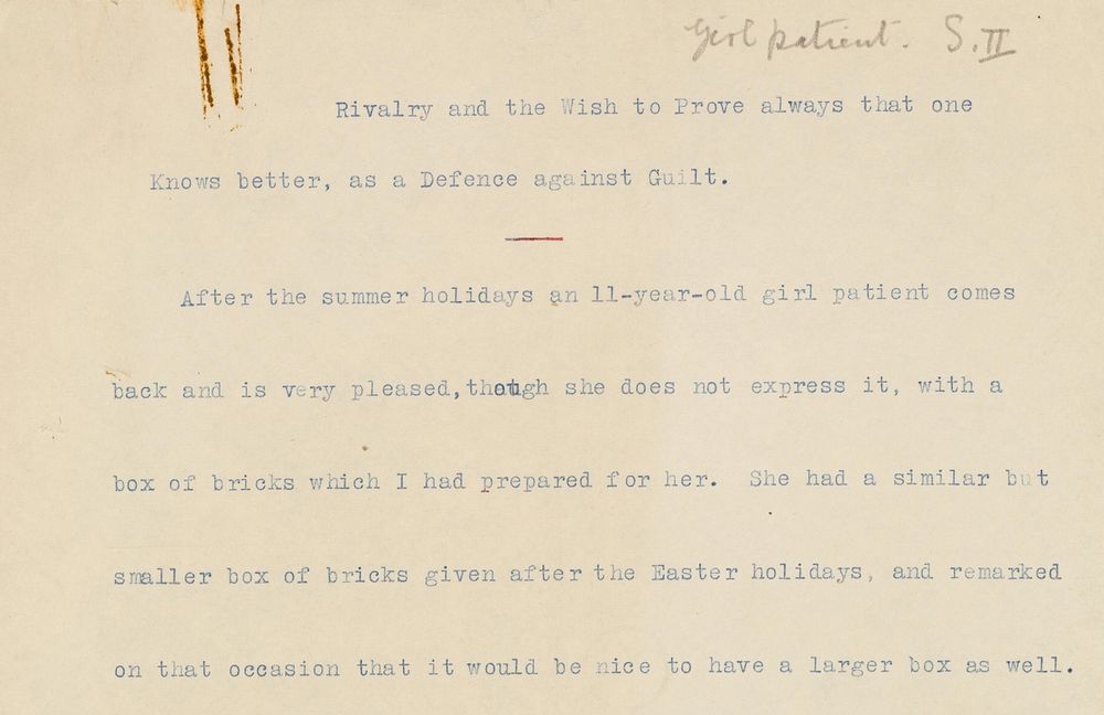 The top part of a yellowed sheet of paper, with typed text: 

Rivalry and the Wish to Prove always that one Knows better, as a Defence against Guilt. 
After the summer holidays an 11-year-old girl patient comes back and is very pleased, though she does not express it, with a box of bricks which I had prepared for her. She had a similar but smaller box of bricks given after the Easter holidays, and remarked on that occasion that it would be nice to have a larger box as well.