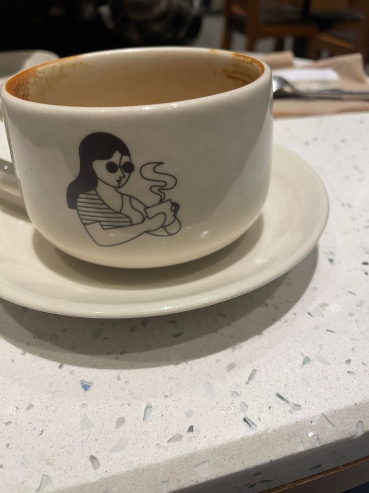 the same cup rotated, there is a clipart style picture of a girl wearing goggles and holding a steaming cup