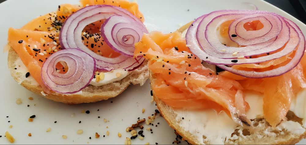 one sliced bagel dressed with cream cheese and smoked salmon and a few thin red onion slices. i am going to eat myself sick 