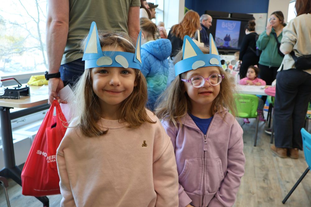 Two children wearing homemade Bluey headbands in the Downtown Library. 