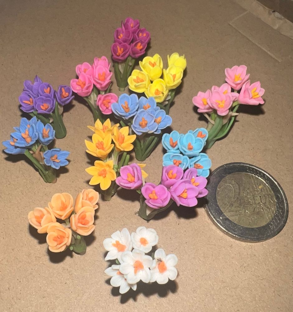 Bunte mini Kroken aus Plastik und ein 2 Euro als größenvergleich. Die Krokusse sind etwa so groß wie ein 2 Eurostück. 