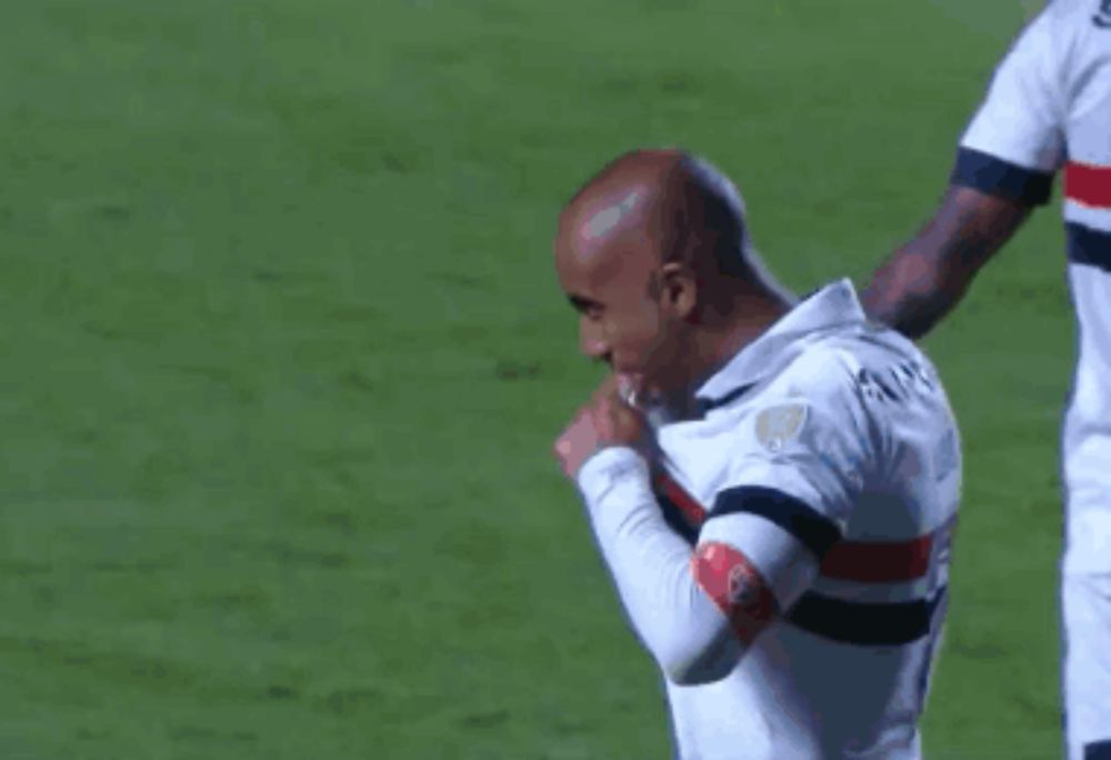 a soccer player wearing a white shirt with a black and red stripe on the arm