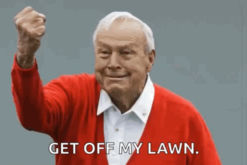 an elderly man in a red sweater is holding his fist in the air and saying get off my lawn .