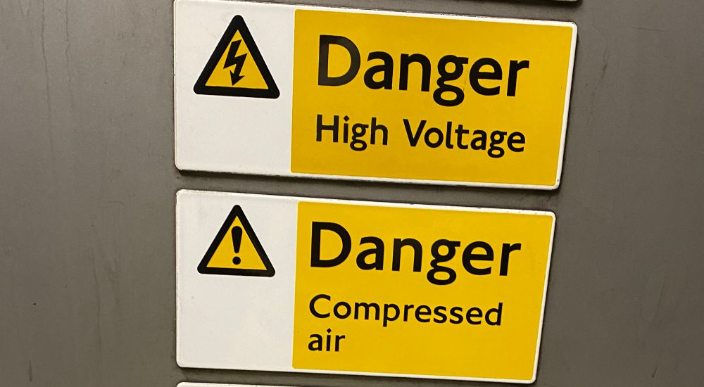 A sign reading: danger! High voltage
A sign underneath reading: danger! Compressed air