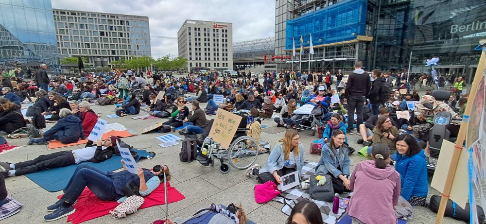 Liegende und sitzende Demonstrierende auf dem Washingtonplatz auf der Liegeddemo 2025 in Berlin. Im Hintergrund ist der Hauptbahnhof zu sehen.