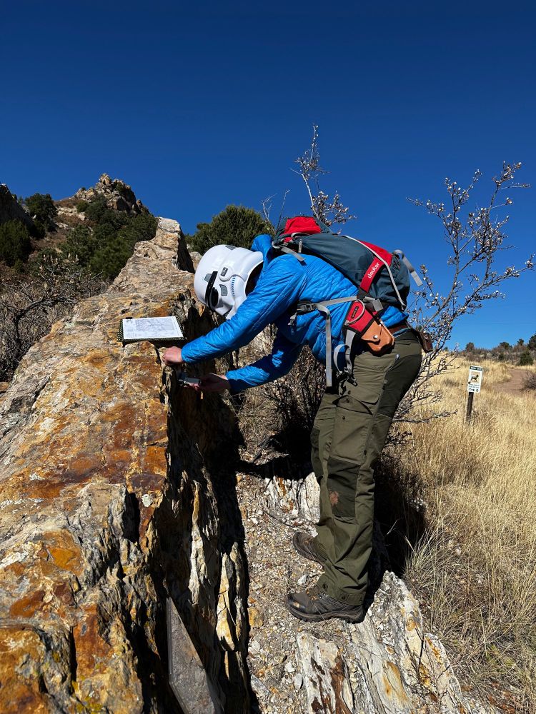 A stormtrooper dresses up as a geologist and attempts to measure the orientation of a steeply dipping rock.