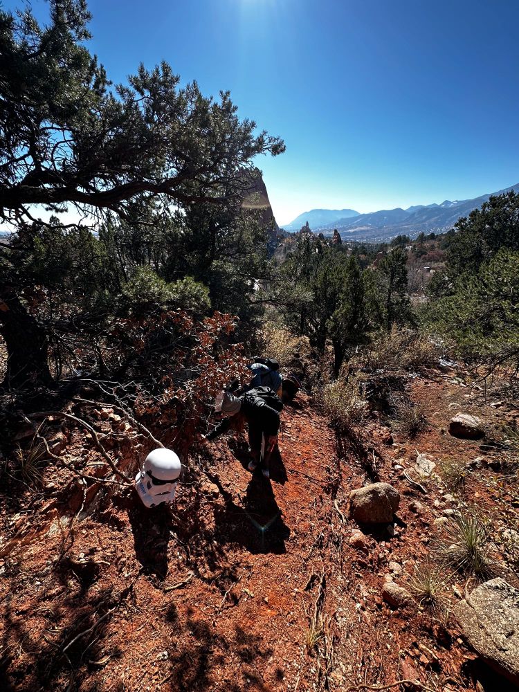 A pair of students take measurements of fault gouge in a pine forest with a stormtrooper helmet for scale.