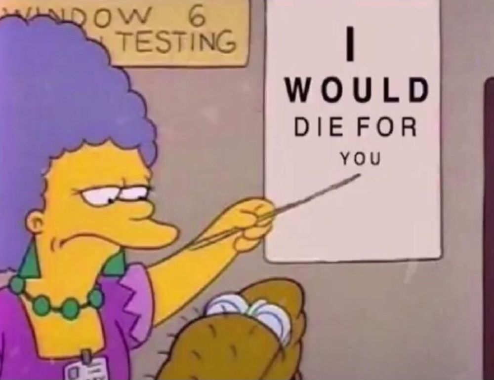 Selma from The Simpsons pointing to a sign that says I would die for you
