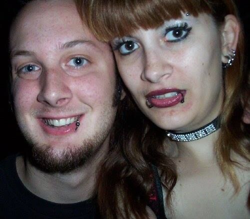 A smiling man and a woman with a blank look on her face with her mouth slightly open.