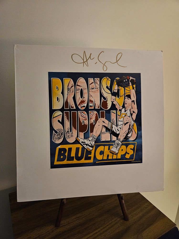 A sleeve for the super limited 2LP edition of Action Bronson and Party Supplies album, 'Blue Chips' on a wooden easel atop of a large Sony speaker. This album was signed by Bronsolino himself.
