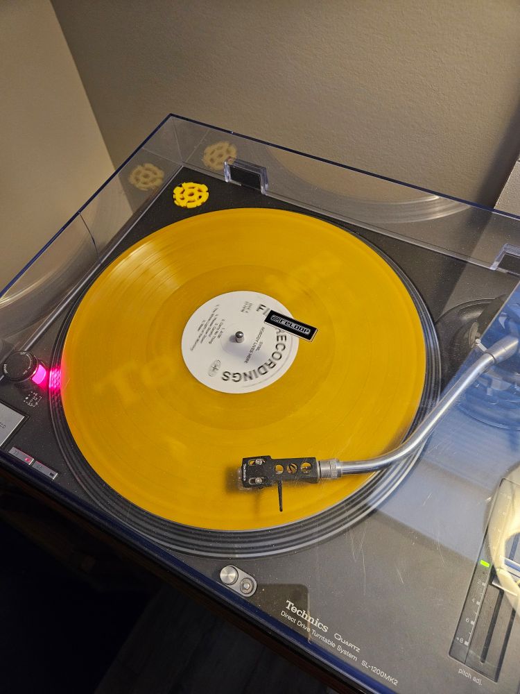 A Technics SL1200-MKII with a bold yellow LP on it. The LP, SYML's new album called 'Nobody Lives Here' has a white centre label with some basic text including the record label and song titles.
