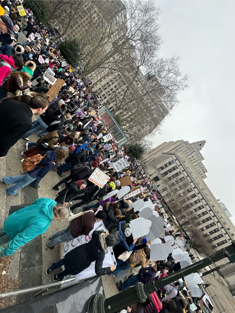 A photo of a crowd of people holding signs and facing toward the federal building across from Foley Square
