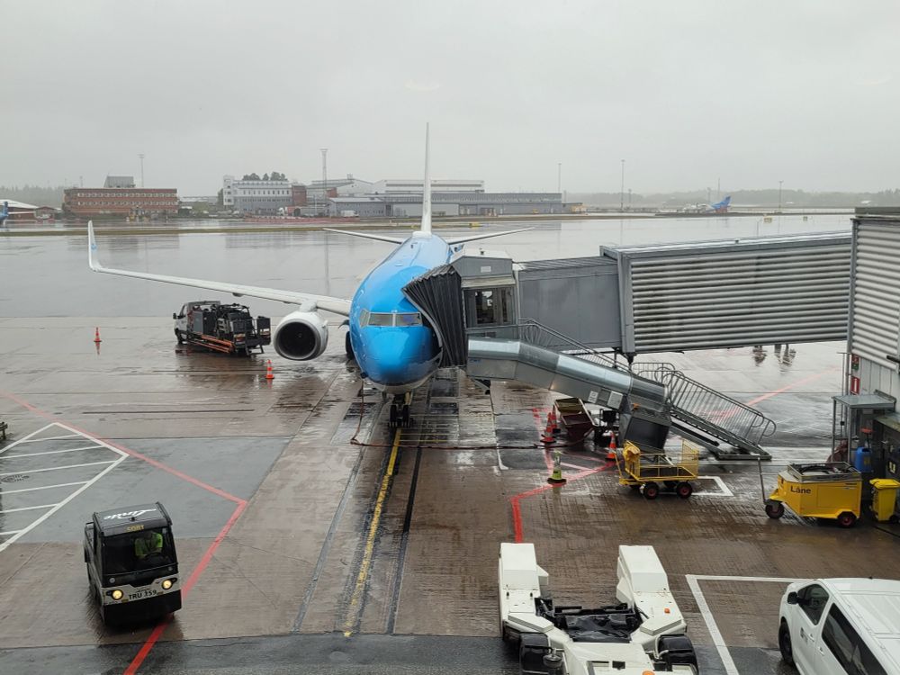 A very rainy airport with a KLM airplane at the gate